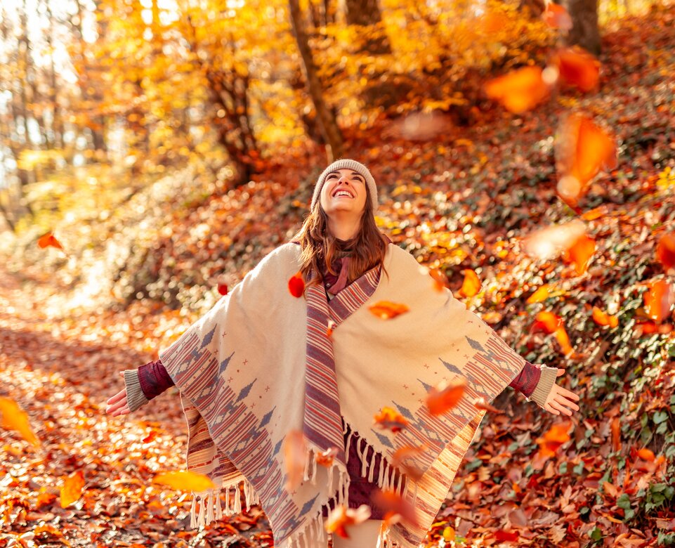 Glückliche junge Frau wirft bunte Herbstblätter im Wald in die Luft | © Envato Elements
