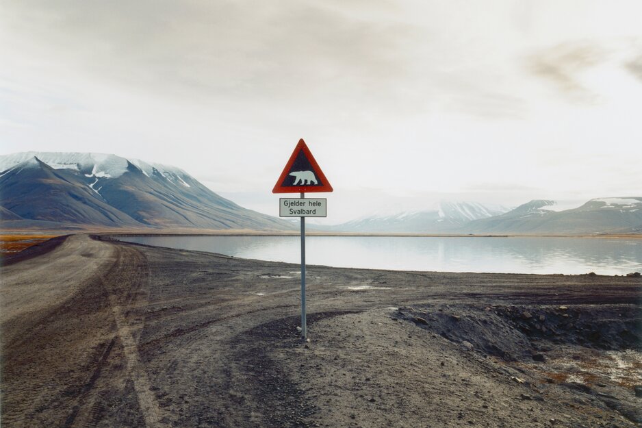 Warnhinweisschild vor Eisbergen, das vor einem See und schneebedeckten Bergen steht | © Envato Elements